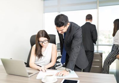 young-partners-reading-document-together-desk-with-colleagues-background